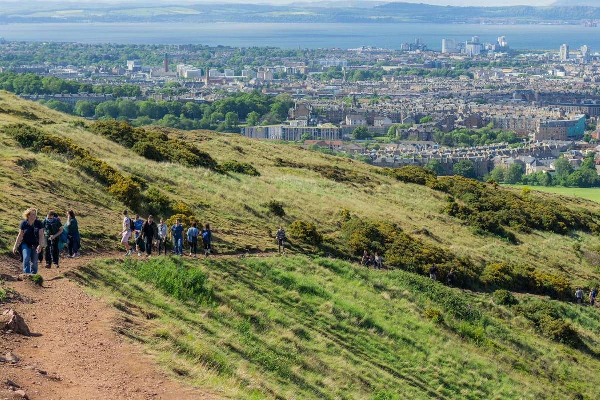 Walkers on the grassy slopes of Arthur's Seat with views over Edinburgh's Southside