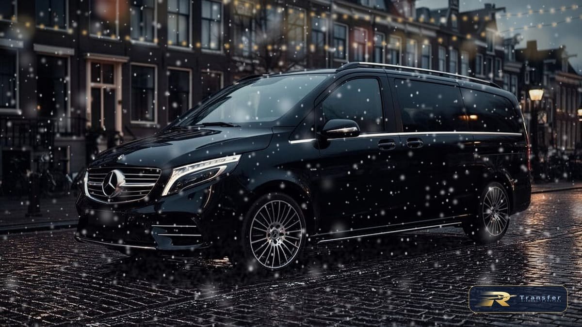 RTransfer black Mercedes V-Class on a snowy cobbled street at Christmas, with festive lights on the buildings behind