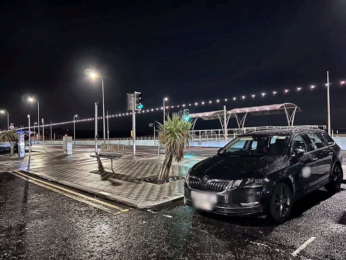 RTransfer black Skoda Octavia private hire car on a wet Edinburgh seafront at night