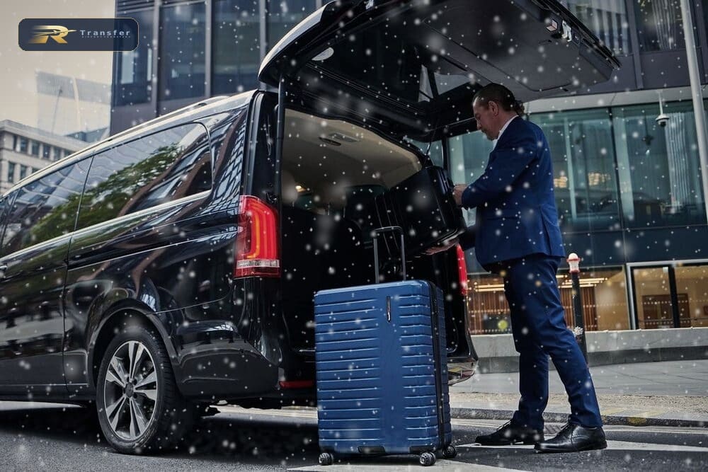 RTransfer driver loading suitcases into a black Mercedes V-Class in the snow before a Christmas airport transfer
